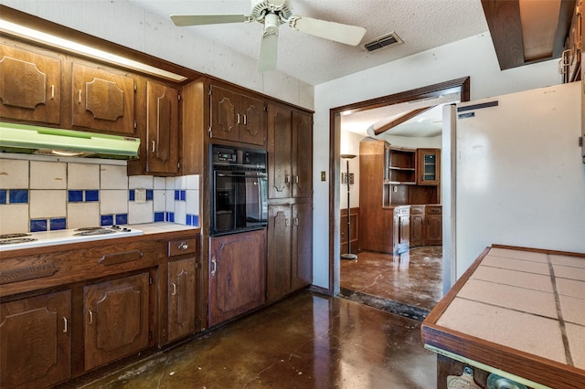 kitchen featuring white appliances, backsplash, ceiling fan, a textured ceiling, and tile counters