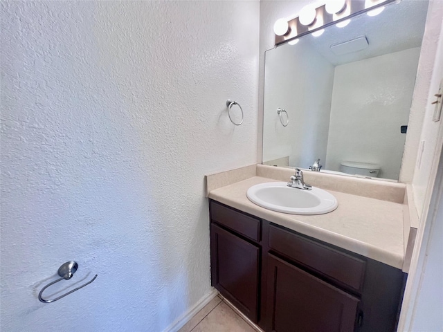 bathroom with tile patterned flooring, vanity, and toilet