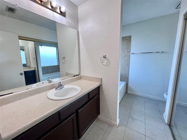 bathroom featuring tile patterned floors, a bathtub, vanity, and toilet