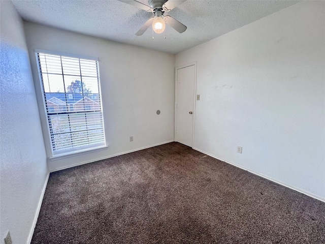 empty room featuring dark colored carpet, ceiling fan, and a textured ceiling