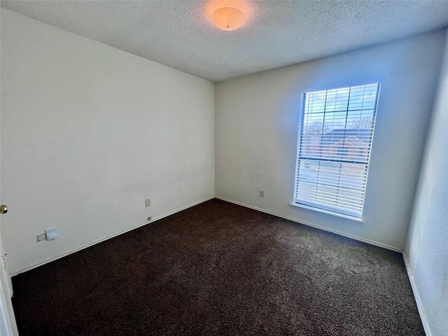 spare room with dark colored carpet and a textured ceiling