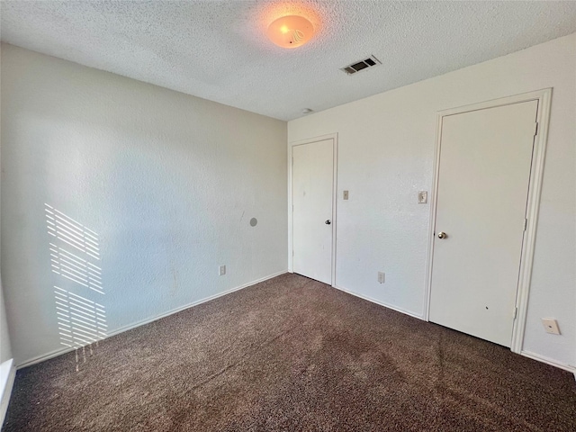 unfurnished bedroom with dark colored carpet and a textured ceiling