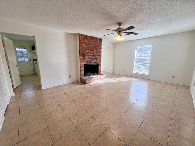 unfurnished living room featuring a fireplace, ceiling fan, light tile patterned flooring, and a textured ceiling