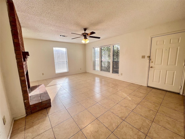 tiled spare room with ceiling fan, a fireplace, and a textured ceiling