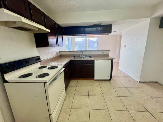 kitchen with dark brown cabinetry, white appliances, sink, and light tile patterned floors