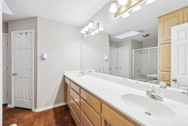 bathroom featuring a skylight, hardwood / wood-style floors, vanity, and a shower with shower door