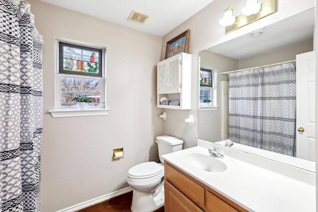 bathroom featuring vanity, a healthy amount of sunlight, toilet, and walk in shower