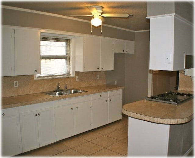 kitchen featuring decorative backsplash, ceiling fan, stainless steel gas cooktop, sink, and white cabinetry