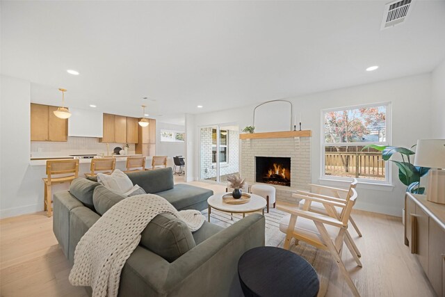 living room with light hardwood / wood-style flooring and a brick fireplace