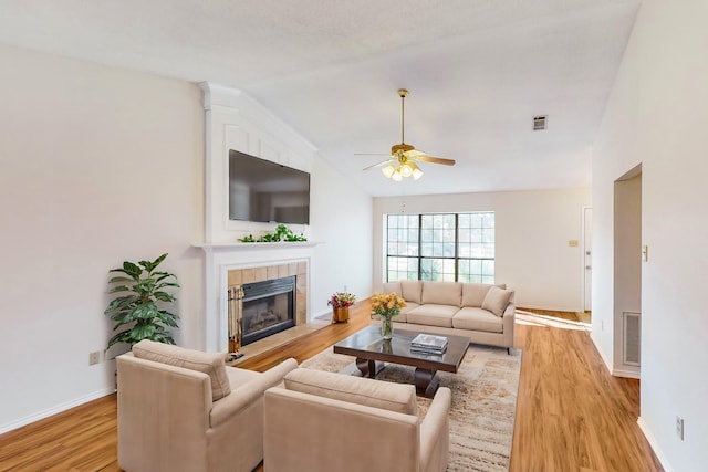 living room with ceiling fan, wood-type flooring, lofted ceiling, and a fireplace