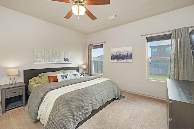 bedroom featuring ceiling fan, light carpet, and multiple windows