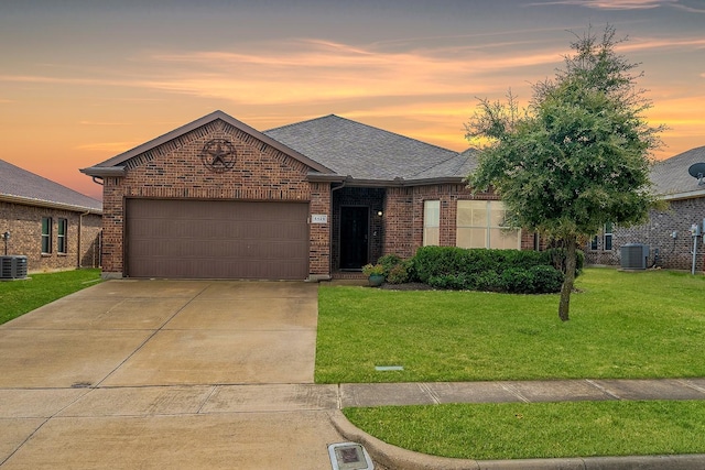 single story home with a garage, central AC unit, and a lawn