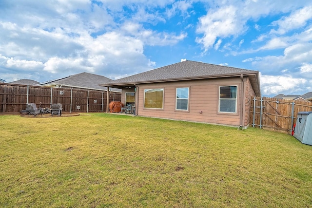 rear view of property featuring a yard and a fire pit