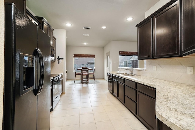 kitchen with dark brown cabinetry, sink, decorative backsplash, light tile patterned flooring, and black appliances