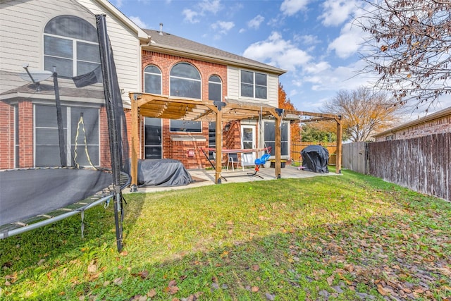 back of house with a pergola, a patio area, a yard, and a trampoline