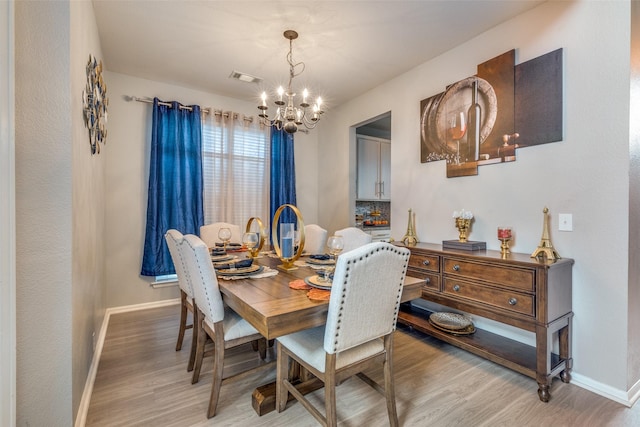 dining space featuring light hardwood / wood-style floors and an inviting chandelier