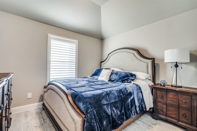 bedroom featuring light wood-type flooring and vaulted ceiling