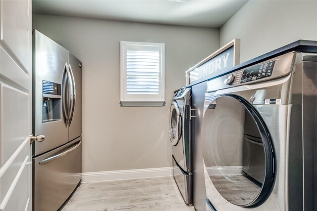 clothes washing area with washer and dryer and light hardwood / wood-style flooring