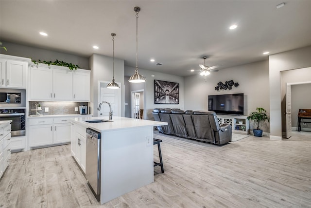 kitchen featuring white cabinetry, sink, an island with sink, pendant lighting, and appliances with stainless steel finishes