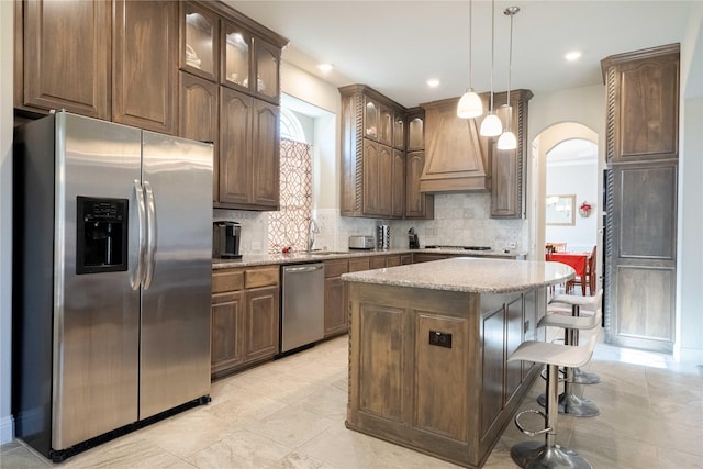 kitchen featuring decorative light fixtures, decorative backsplash, a breakfast bar, a kitchen island, and appliances with stainless steel finishes