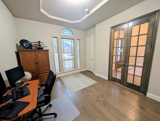 office area with a tray ceiling, wood finished floors, french doors, and baseboards