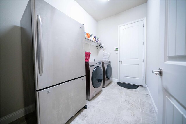 clothes washing area with washing machine and clothes dryer, laundry area, and baseboards