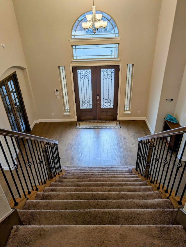 foyer featuring wood-type flooring, a wealth of natural light, and a towering ceiling