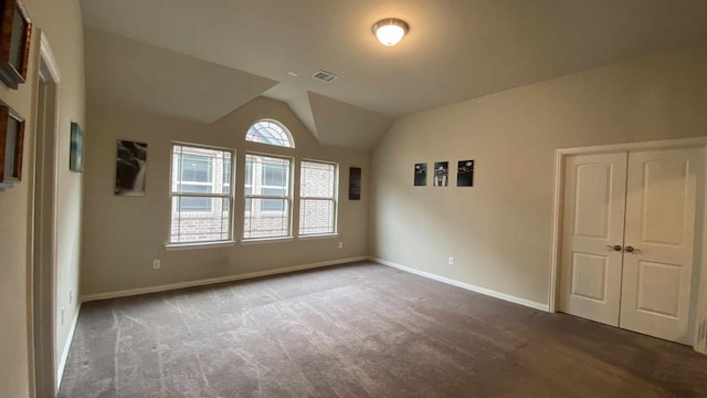 unfurnished bedroom with lofted ceiling, carpet flooring, baseboards, and visible vents