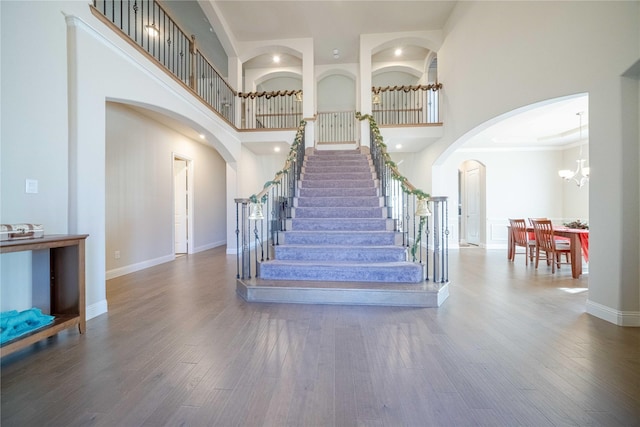 staircase featuring a high ceiling, an inviting chandelier, and wood-type flooring