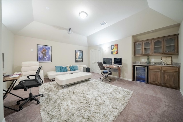 carpeted office with a raised ceiling, wine cooler, vaulted ceiling, and indoor wet bar