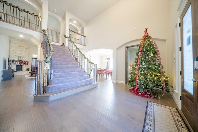 entrance foyer featuring wood-type flooring, a towering ceiling, and a fireplace