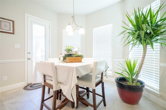 dining room with an inviting chandelier, light tile patterned flooring, and baseboards