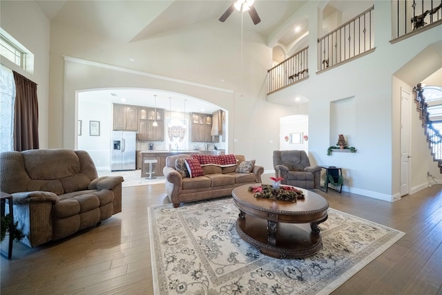 living room featuring ceiling fan, a towering ceiling, and hardwood / wood-style flooring