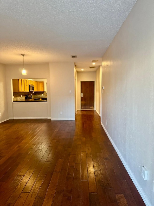 unfurnished living room with a textured ceiling and dark hardwood / wood-style flooring