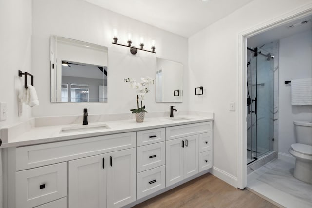 bathroom with wood-type flooring, vanity, toilet, and a shower with door