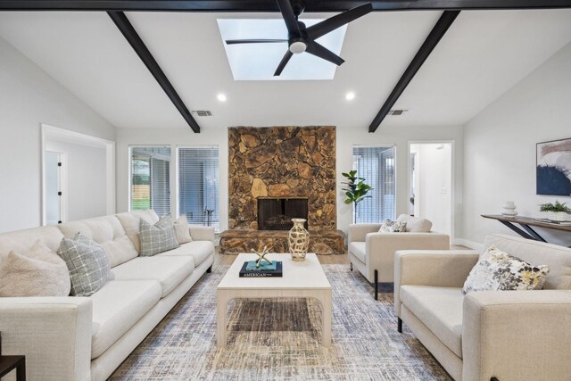 living room featuring a fireplace, wood-type flooring, lofted ceiling with skylight, and ceiling fan