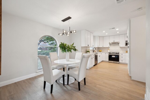 dining room featuring light wood-type flooring and a notable chandelier