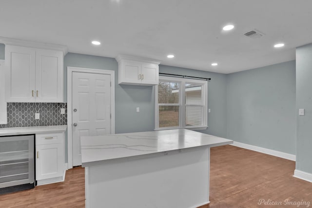 6263 Bain Blvd, Keithville, LA 71047 - kitchen featuring visible vents, tasteful backsplash, light wood finished floors, beverage cooler, and white cabinetry