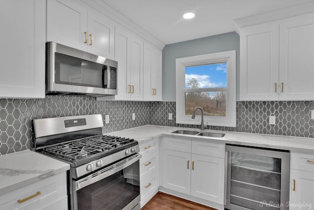 kitchen featuring sink, white cabinetry, stainless steel appliances, beverage cooler, and light stone countertops