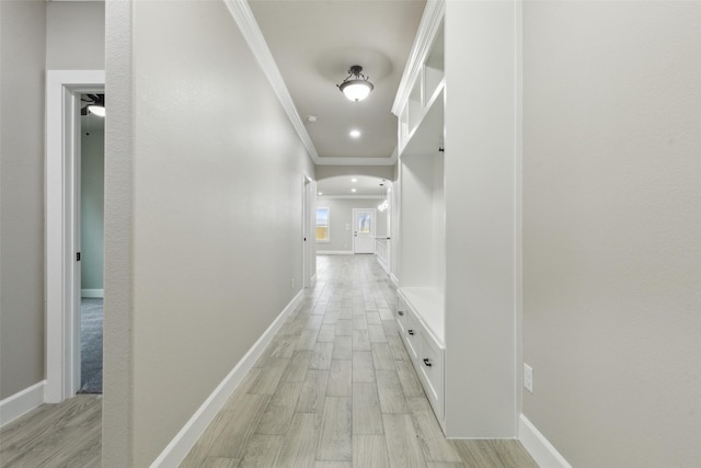 corridor with light hardwood / wood-style flooring and crown molding