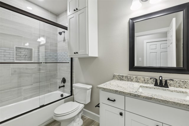 full bathroom featuring toilet, combined bath / shower with glass door, wood-type flooring, and vanity