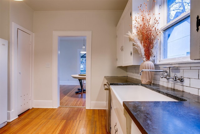 kitchen featuring decorative backsplash, white cabinetry, crown molding, and light hardwood / wood-style flooring