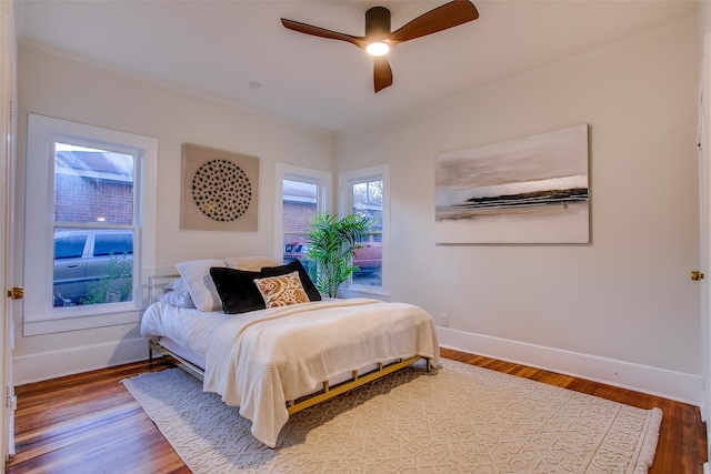 bedroom with hardwood / wood-style flooring, ceiling fan, and ornamental molding