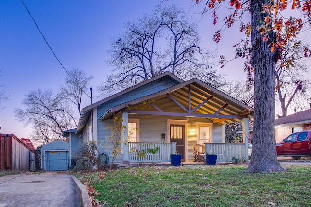 bungalow-style home with an outbuilding, a porch, a garage, and a lawn