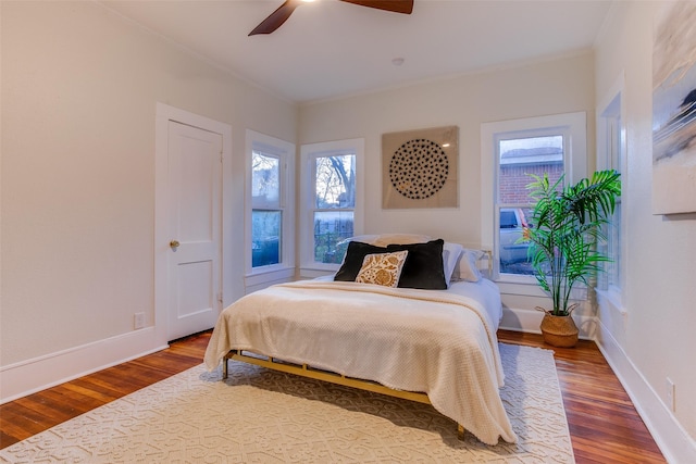 bedroom with multiple windows, ceiling fan, and wood-type flooring