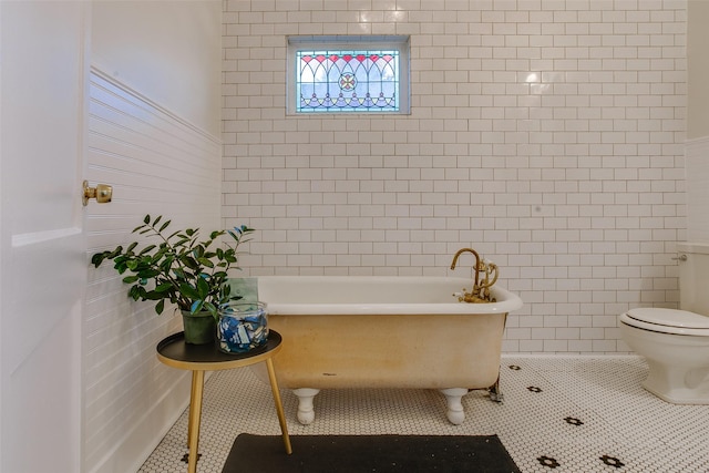 bathroom featuring tile patterned flooring, toilet, a bathtub, and tile walls