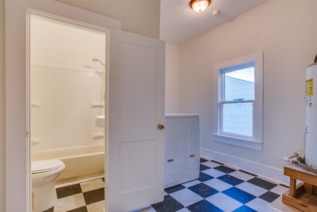 bathroom with electric water heater, toilet, shower / bathing tub combination, and washer / dryer