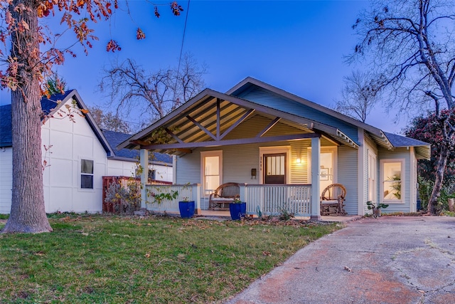 bungalow featuring covered porch and a front lawn