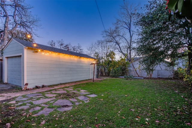 yard at dusk with a garage and an outbuilding