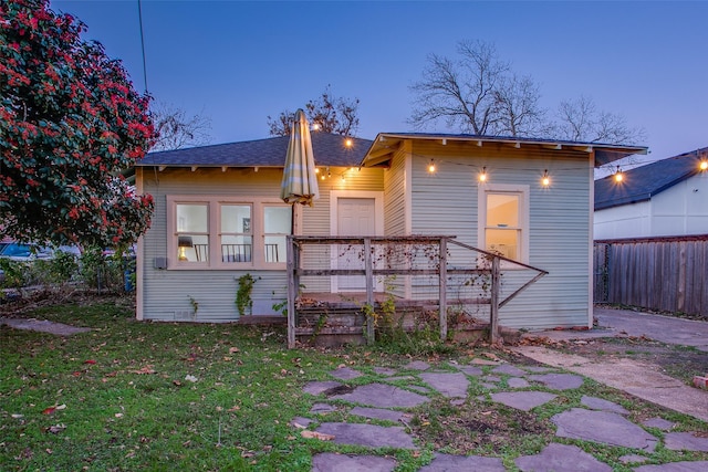 back house at dusk featuring a yard